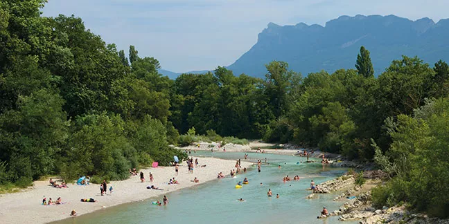 Des baigneurs profitent de la rivière Drôme, avec une vue dégagée sur les Trois Becs en arrière-plan.